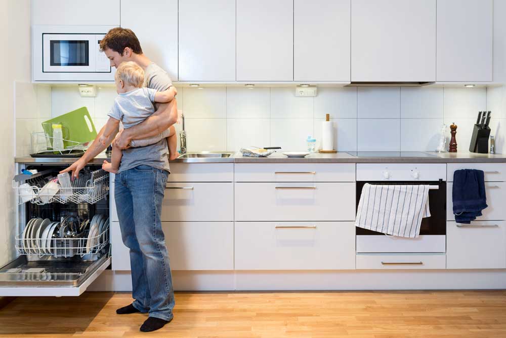 Father holding his child while stacking dishwasher